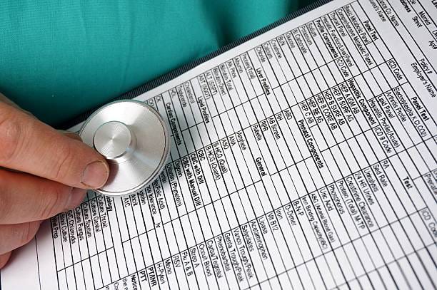 A-person-holds-a-stethoscope-over-a-medical-form.